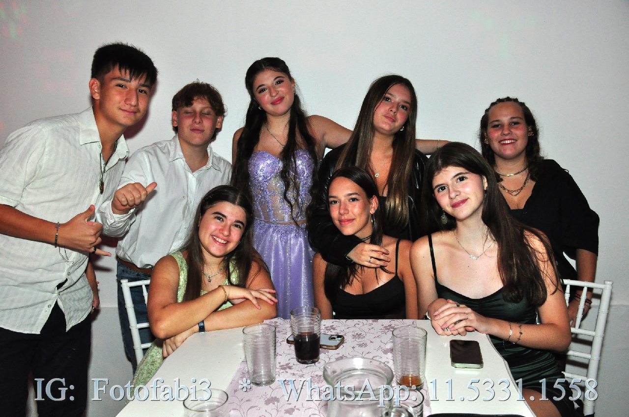 Grupo de amigas y amigos posando junto a la quinceañera en una mesa