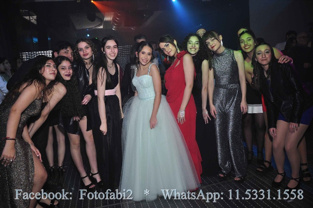 Grupo de invitados posando con la quinceañera en una pista con luces de colores